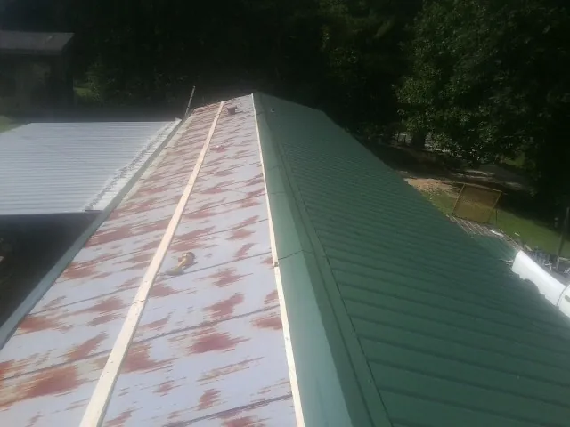 Old rusted panels beside newly installed green metal roofing — Wind Damage Roof Repair by Roofing Brothers in Lake Saint Louis