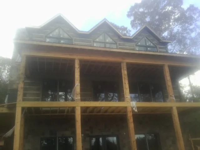 Dormers and porch framing on a large log home under construction — Roof Coating work by our crew in Lake Saint Louis