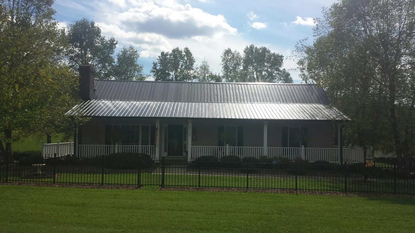 Gray metal roof on a brick ranch with a full width front porch — Gutter Guard Installation work by our crew in Lake Saint Louis