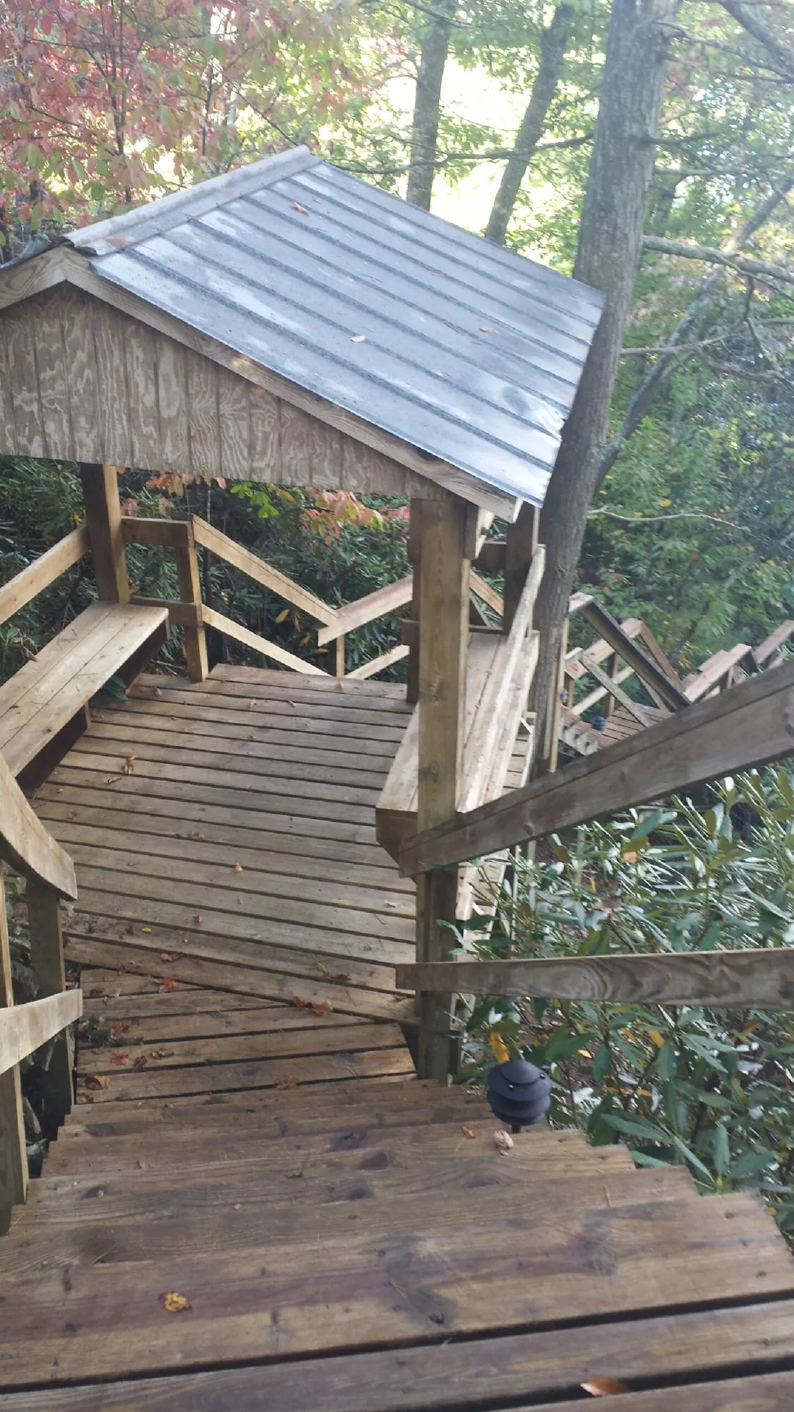 Metal roofed shelter over wooden steps on a wooded walkway — Skylight Repair & Installation work by our crew in Lake Saint Louis