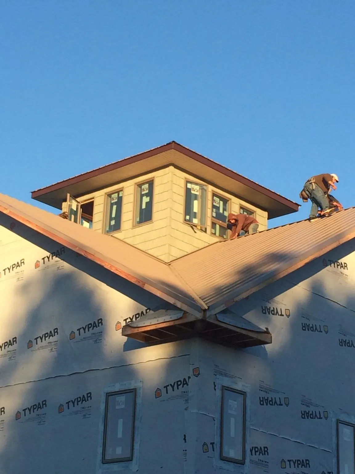 Roofers working around a rooftop cupola on a new metal roof at sunset — Roof Waterproofing in Lake Saint Louis by Roofing Brothers